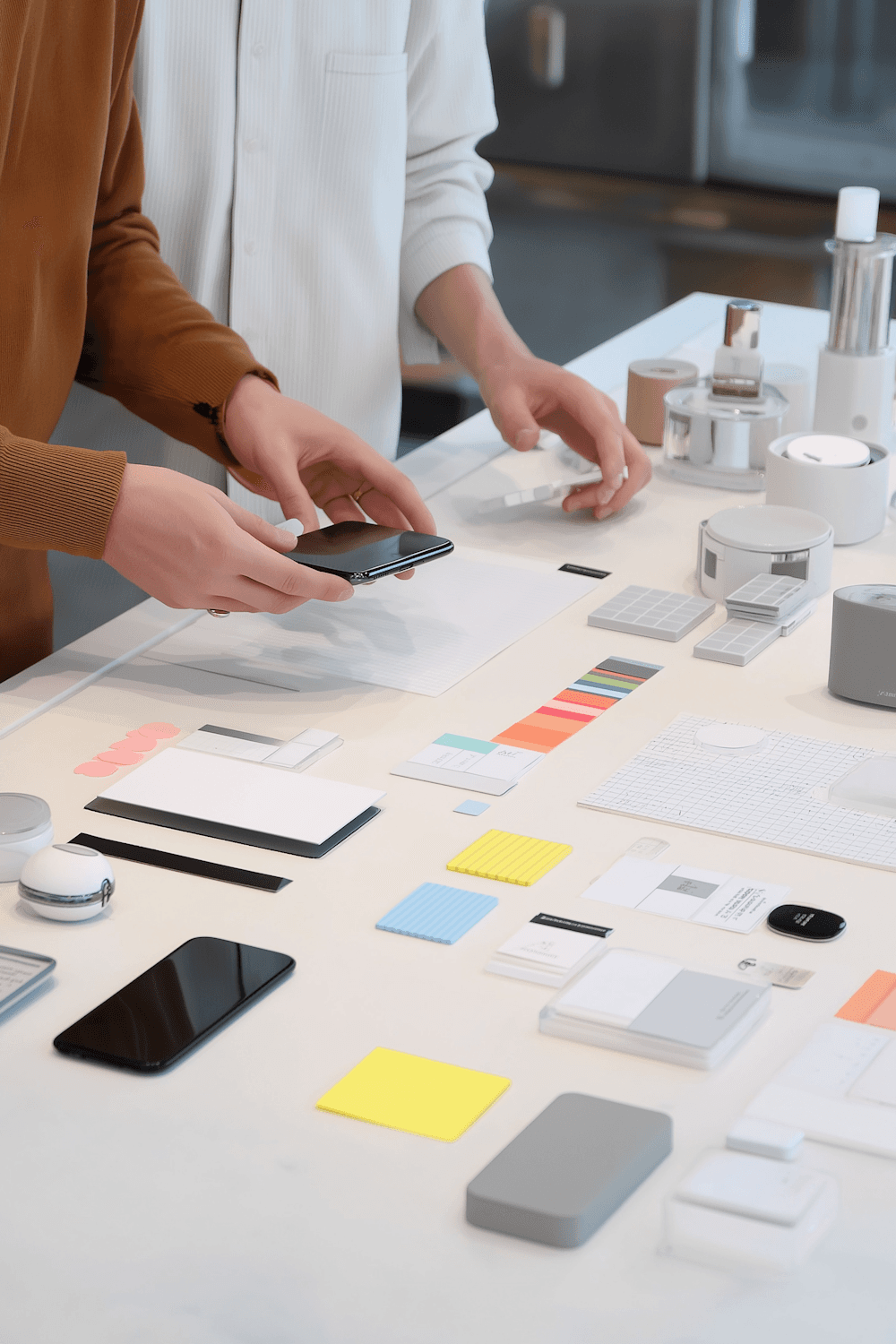 Two people arranging colour swatches and phones on a studio table